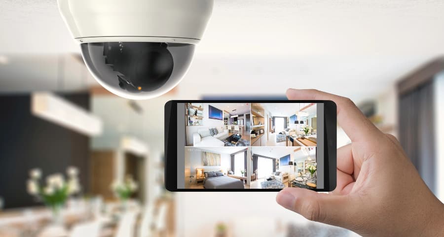 Homeowner holding smartphone with video feed from security cameras in Mobile